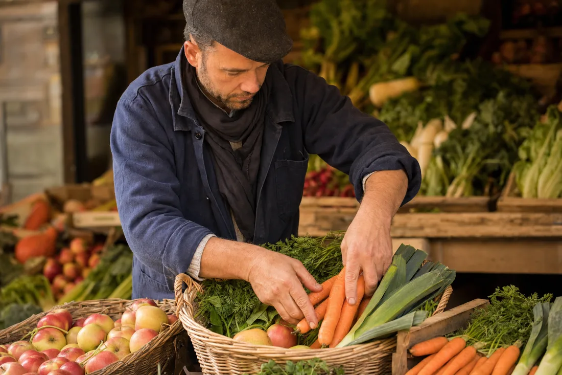 Le primeur disposant des légumes frais dans un panier en osier